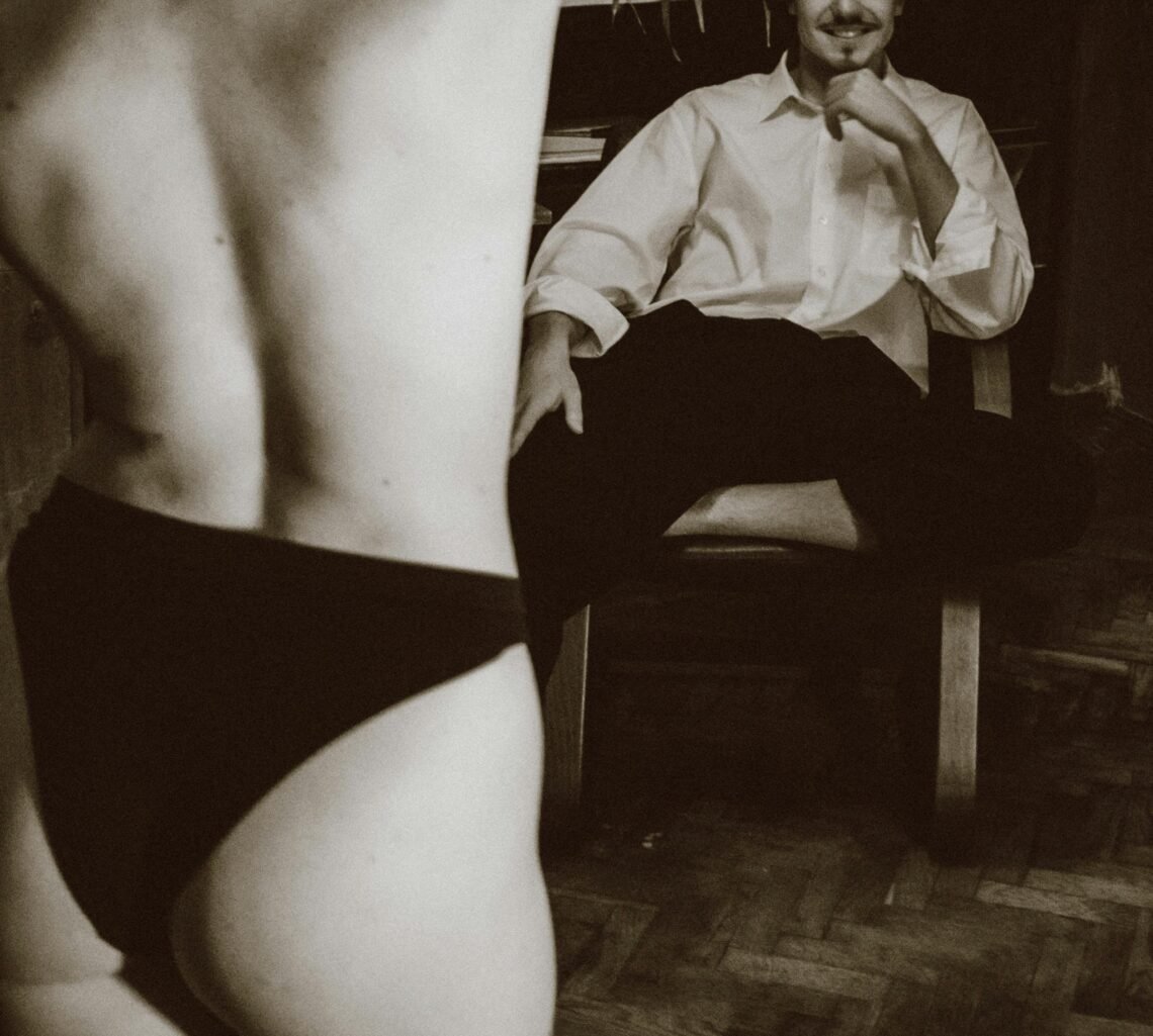 Back View of a Shirtless Woman, and Man on a Chair Starring