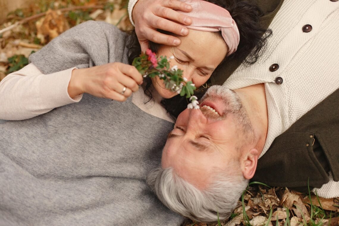 Happy senior couple in love with bunch of fresh flowers in nature