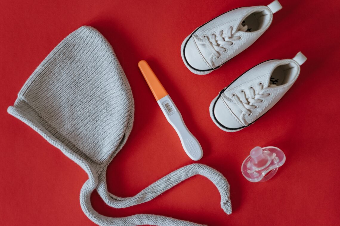 Close-Up Shot of Pregnancy Test Near Baby's Things